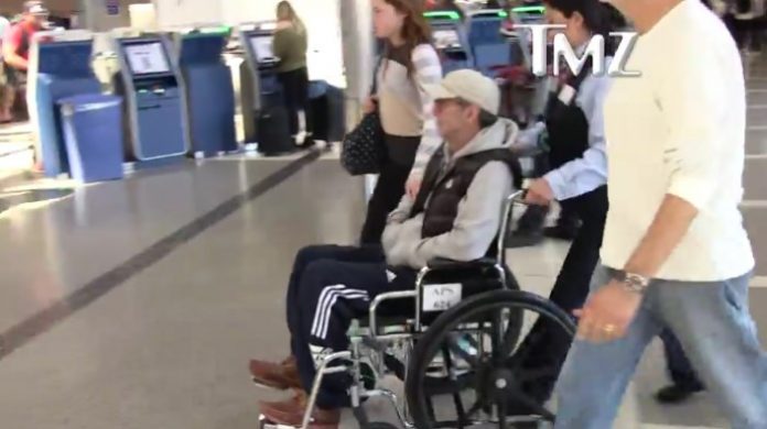 Eric Clapton em cadeira de rodas no aeroporto