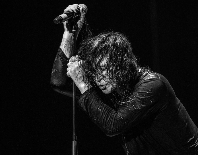 Ozzy Osbourne se apoiando em microfone