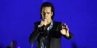 Nick Cave no palco cantando ao microfone